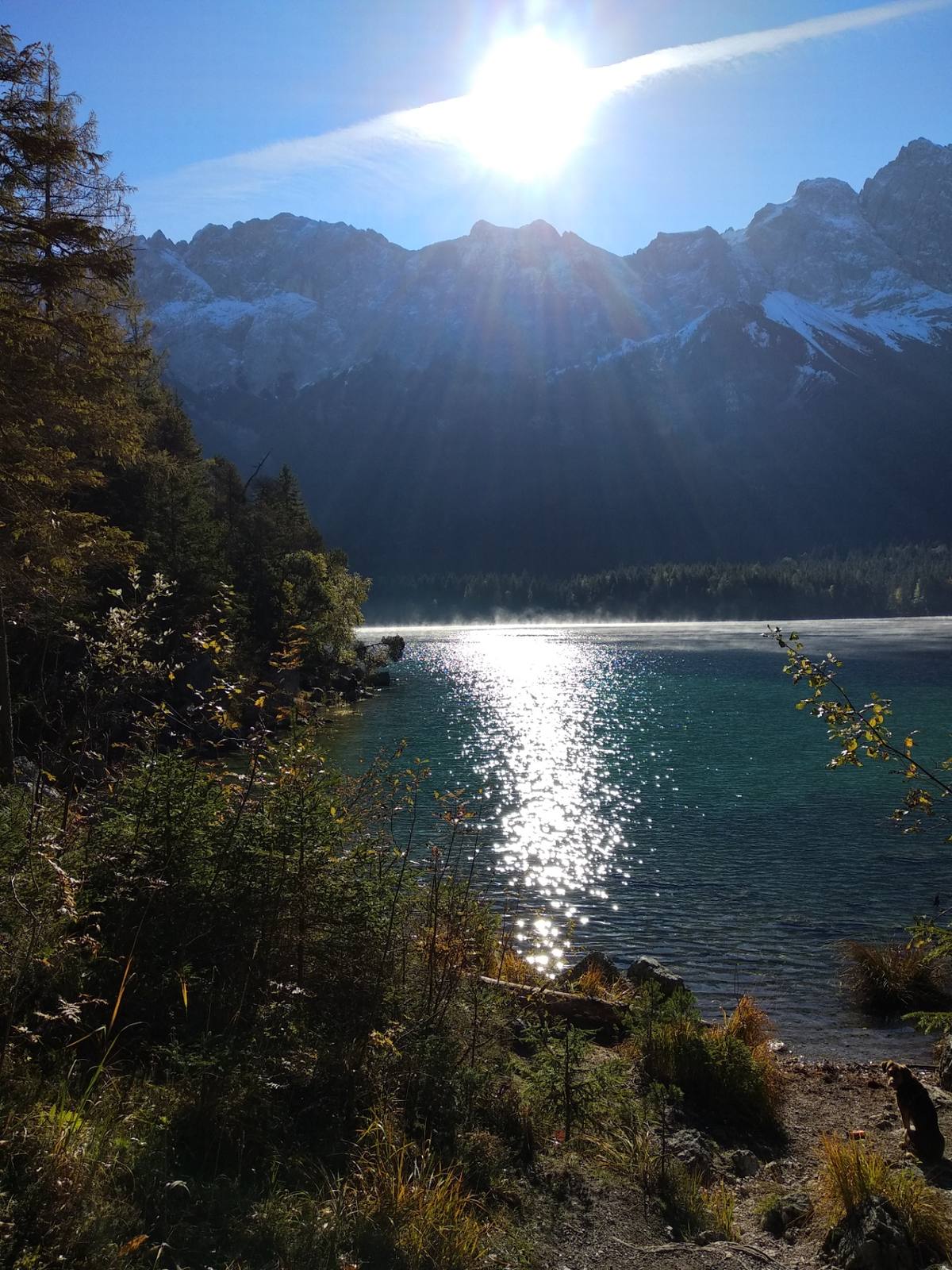 Gegenlicht über dem Eibsee — Sonne über den Bergen, Spiegelung im See, Herbstlaub am Ufer