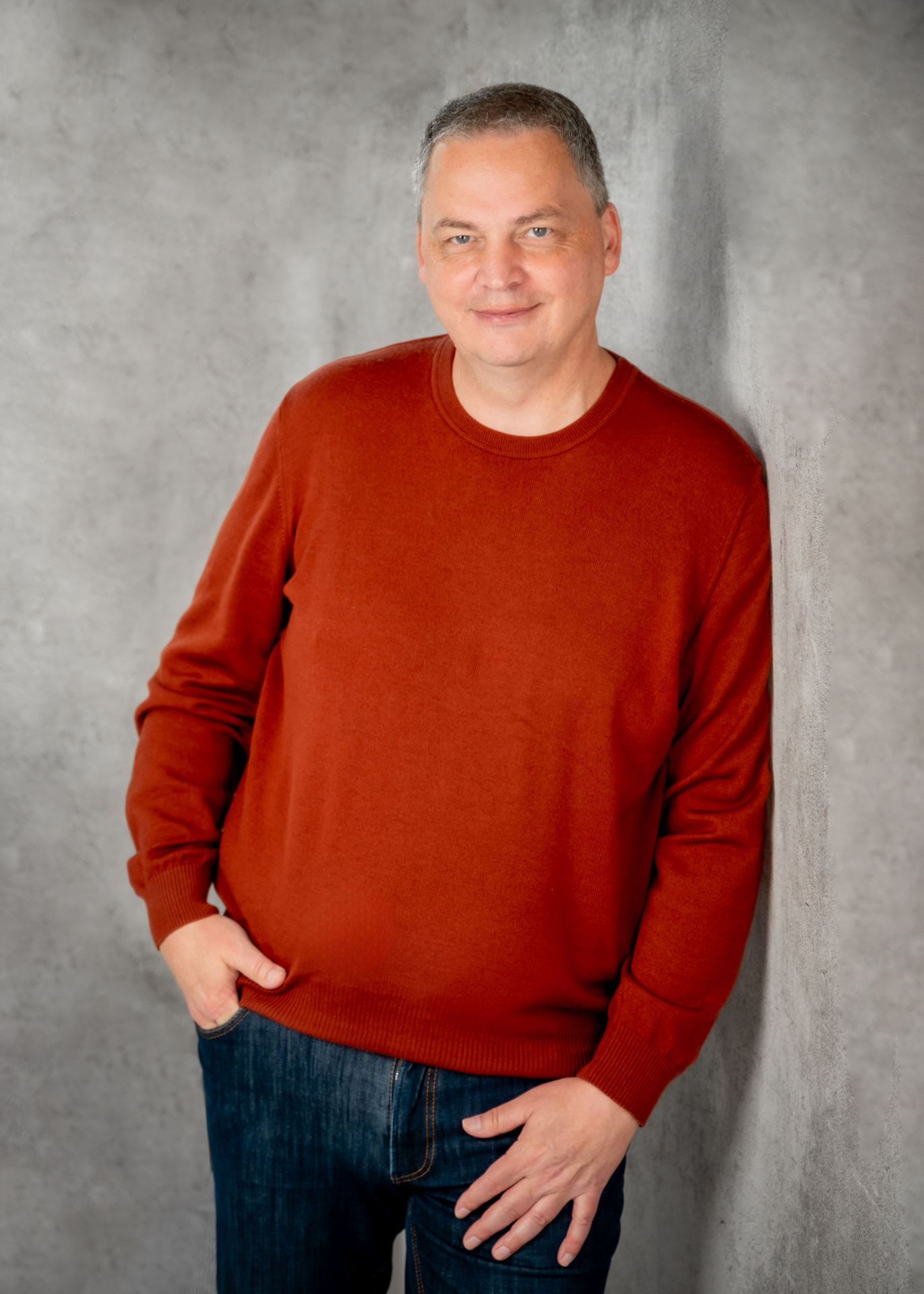 Porträt von Jörg Hörmann in rostbraunem Pullover, ruhiger, aufmerksamer Blick